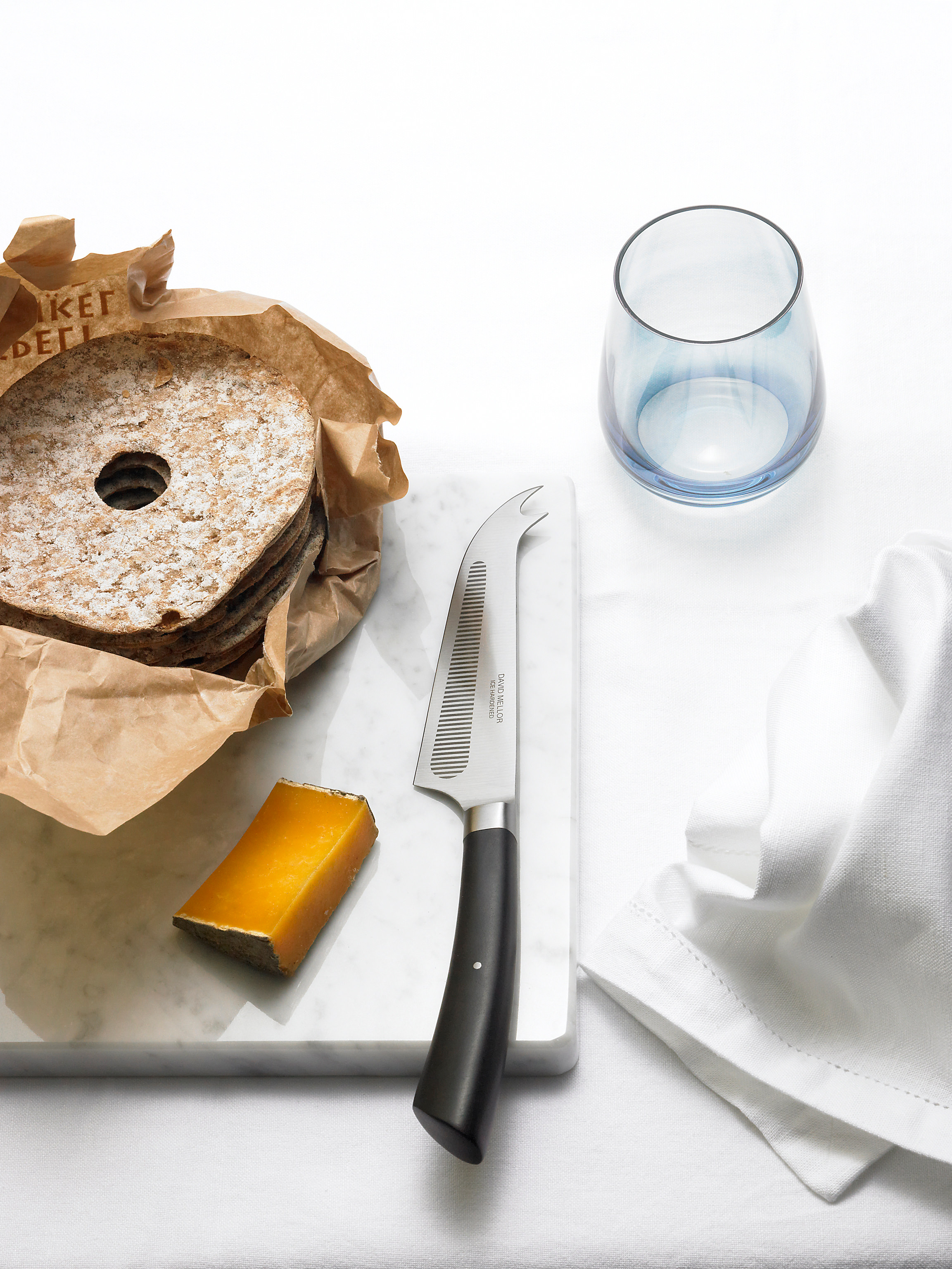 Cheese and bread on a marble board with knife.